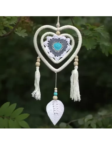 atrapasueños corazón tonos malvas y azules colgado en el exterior sobre plantas