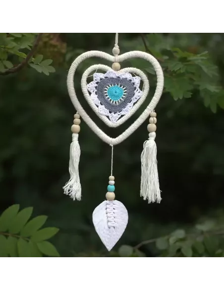 atrapasueños corazón tonos malvas y azules colgado en el exterior sobre plantas
