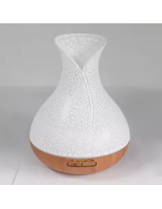 Difusor de aromas color nácar con base de madera y forma de jarrón con cambio de color y temporizador sobre un mueble de madera 2