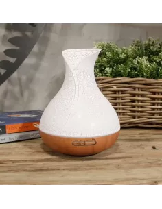 Difusor de aromas color nácar con base de madera y forma de jarrón con cambio de color y temporizador sobre un mueble de madera